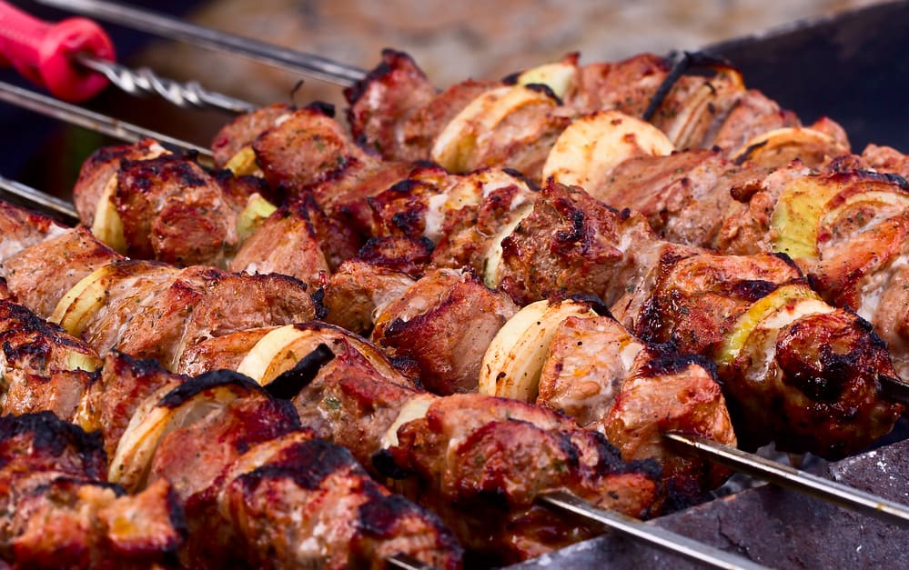 Juicy slices of meat with sauce prepare on fire (shish kebab) for tailgating